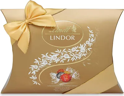 A golden pillow box of Lindt Lindor chocolates, tied with a gold ribbon and decorated with white floral patterns.
