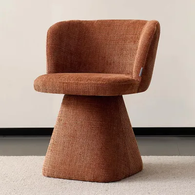 A single orange-brown upholstered swivel chair with a flared base sits on a light-colored rug.