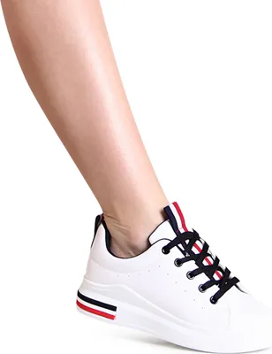 A close-up shot of a person's lower leg and foot wearing a white sneaker.