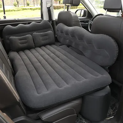 An inflatable mattress is set up in the back of a car, filling the space between the seats.
