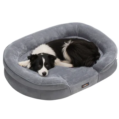 A border collie dog is lying on a gray dog bed.
