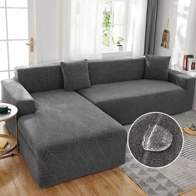 A sectional sofa covered in a patterned dark gray slipcover, shown in a living room setting. A close-up inset highlights the fabric's water-repellent feature with a water droplet.