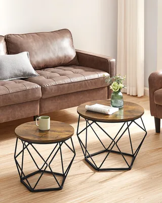 A living room scene with a brown leather sofa and two round coffee tables with geometric black bases.