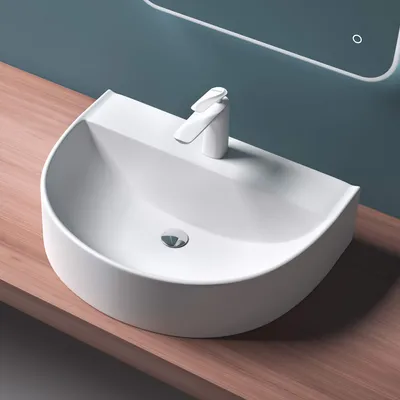 A white ceramic sink with a modern faucet sits on a wooden countertop against a blue wall. A reflection of a mirror with a light is visible in the background.