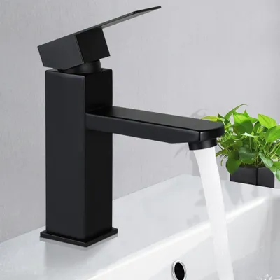 A black modern faucet in a bathroom, with water running into a sink.