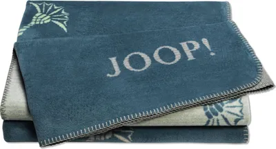 A folded blue blanket with a light blue pattern and the brand name "JOOP!" printed on it.