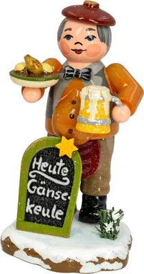 A wooden figurine of a man holding a plate of food and a mug of beer, standing in front of a chalkboard sign.