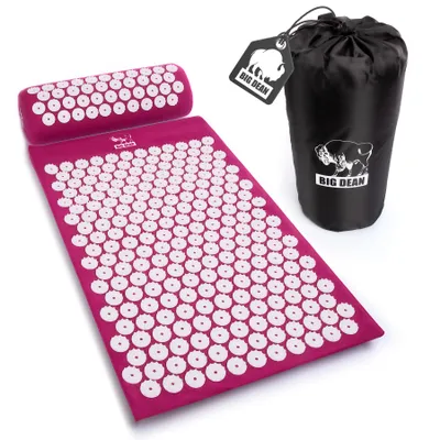 A pink acupressure mat and pillow with white spikes, along with a black storage bag, are displayed on a white background.