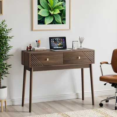 A modern desk setup with a laptop, office supplies, and a decorative plant.