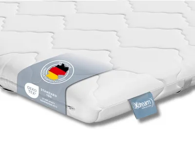 A close-up of a white mattress topper with labels attached.