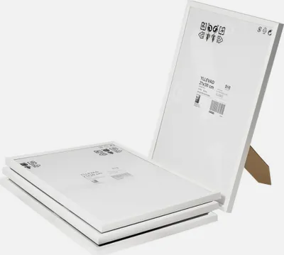 A stack of white IKEA picture frames with one frame standing upright.