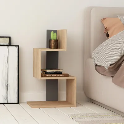 A small, modern side table with a zig-zag design, placed next to a bed.