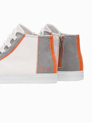 A close-up view of the back and side of two white high-top sneakers with gray and orange accents.
