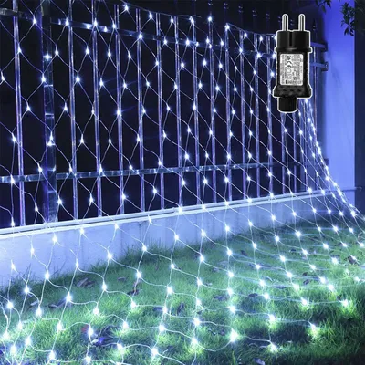A net of white LED lights is draped over a fence and onto the grass, illuminating the scene.