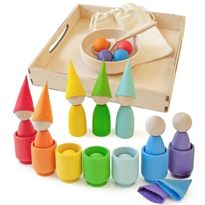 A collection of wooden Montessori toys, including peg dolls with cone hats, cups, and balls, arranged on a wooden tray.