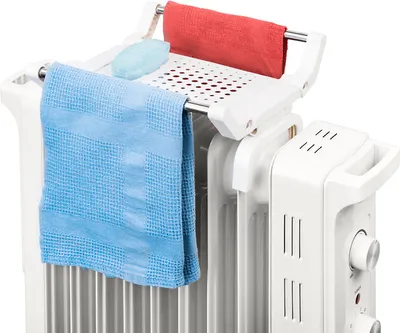A white electric heater with a drying rack attached, holding two towels and a bar of soap.