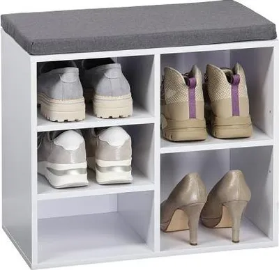 A white shoe cabinet with a gray seat cushion on top, filled with various shoes.