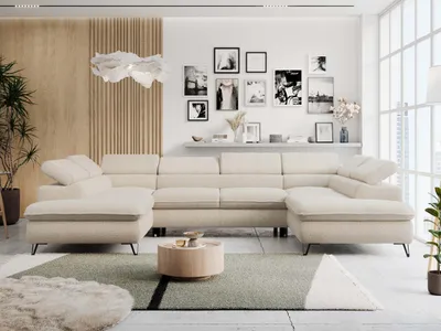 A modern living room with a large U-shaped sectional sofa in beige boucle fabric, a round wooden coffee table, and a gallery wall of framed pictures.