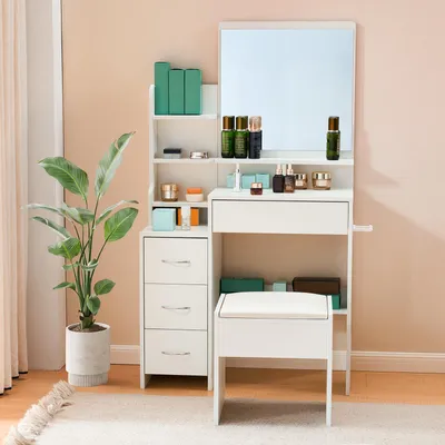A white vanity table with a mirror, drawers, and a stool, next to a large potted plant.