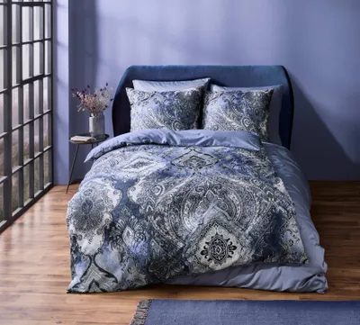 A bed with blue and gray patterned bedding is shown in a room with a large window and purple walls.