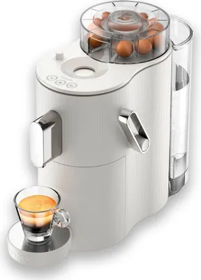 A white coffee machine with a clear water reservoir, dispensing a shot of espresso into a glass cup.