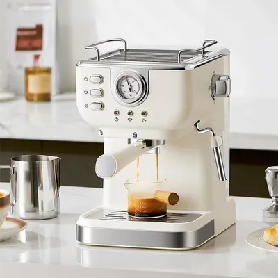 A cream-colored espresso machine is shown on a white countertop, with coffee brewing into a small glass beaker.