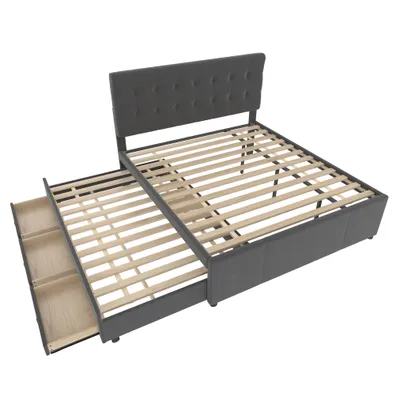 A dark gray upholstered bed frame with a tufted headboard and a pull-out trundle bed with drawers underneath, shown from a diagonal angle on a white background.
