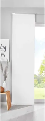 A white panel curtain is shown hanging in front of a window with a view of trees and sky. To the left, a framed picture with text and a vase with dried grass are visible.