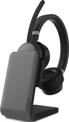 A black and gray Lenovo headset is placed on its charging stand.