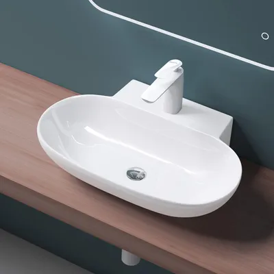 A white ceramic sink with a modern faucet is mounted on a wooden countertop against a teal wall.