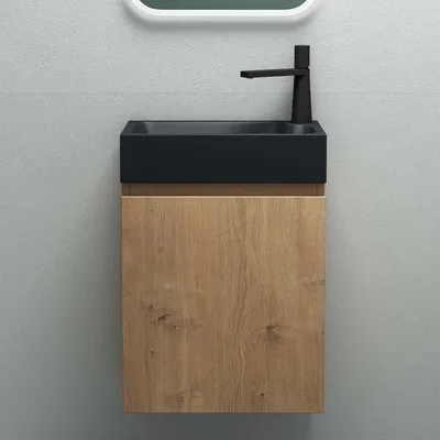 A modern bathroom vanity with a black sink and a wood-grain cabinet against a gray tiled wall.