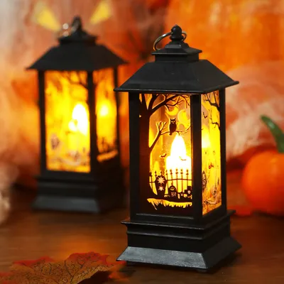 Two Halloween-themed lanterns are displayed on a wooden surface, with a blurred orange background suggesting a festive setting.