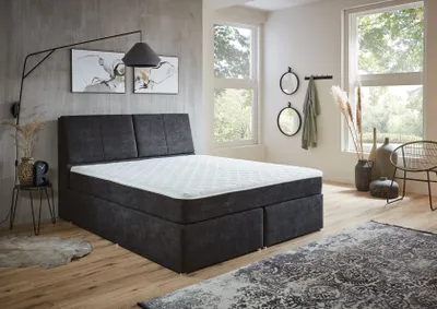 A bedroom scene with a bed, rug, and decor.