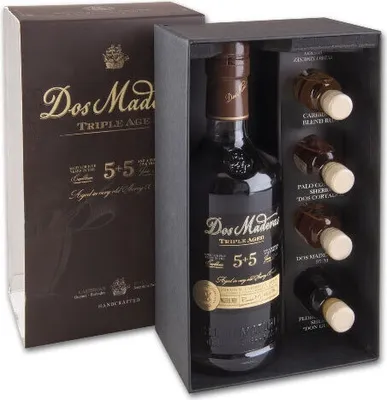 A gift set of Dos Maderas rum, featuring a full bottle and four smaller tester bottles, presented in a dark grey box with a brown outer sleeve.