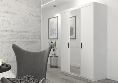 A white wardrobe with mirrored doors is shown in a modern interior setting, next to a gray armchair.