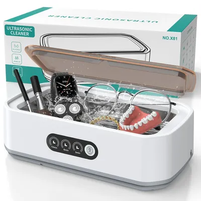 An ultrasonic cleaner with various items inside, such as glasses, jewelry, and dentures, with water splashing.