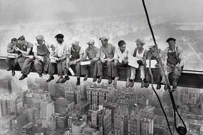 Eleven construction workers are sitting on a steel beam high above New York City, eating lunch.