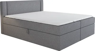 A gray boxspring bed with a white mattress and a headboard, shown from a side angle against a white background.
