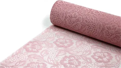 A roll of pink lace fabric with a floral pattern, partially unrolled on a white surface.