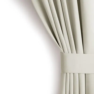A close-up of a cream-colored blackout curtain with pleats and a tie-back.