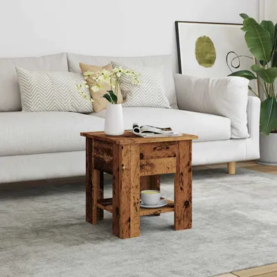 A wooden side table with a cup of tea and a magazine on it, placed in a living room setting next to a sofa.