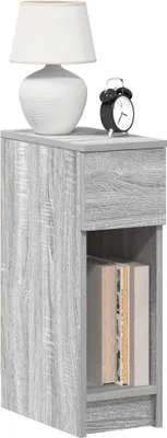A bedside table with a lamp and an alarm clock on top, and books on the shelf.