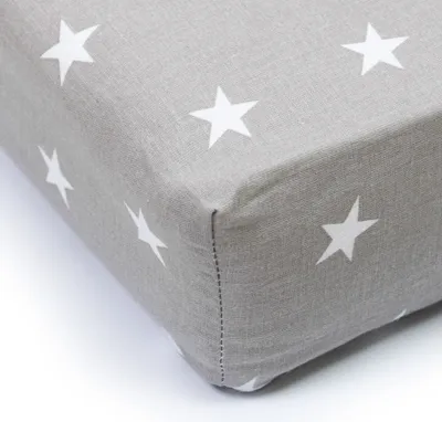 A close-up view of a corner of a crib sheet with a star pattern.