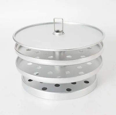 A silver-colored kitchen appliance with multiple perforated trays stacked on top of each other, topped with a lid and a small handle.