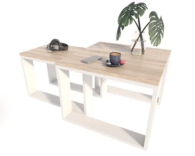 A modern coffee table with a wood top and white geometric base, styled with headphones, a smartphone, a cup of coffee, and a plant.