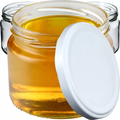 Three glass jars filled with honey, one with a white lid placed on top.