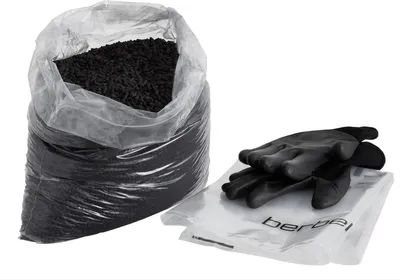 A bag of black pellets and a pair of black gloves on a clear plastic sheet.