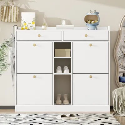A white shoe cabinet with multiple compartments and drawers, placed in a room with a rug and a mirror in the background.