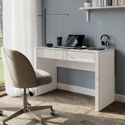 A modern white desk with a laptop, headphones, and a coffee cup, next to a chair in a well-lit room.