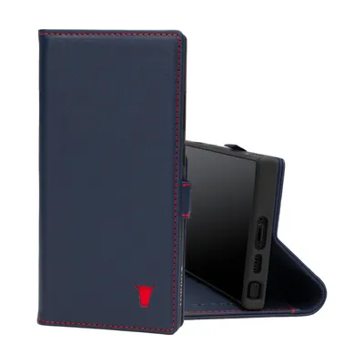 A dark blue leather phone case with red stitching and a red bull logo is shown open, revealing a black smartphone inside. The case is standing upright, with the phone angled slightly to the right.